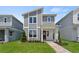 Modern two-story home with gray siding, stone accents, red door, and manicured lawn at 2046 Education St, St Cloud, FL 34771