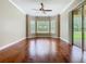 Bedroom with hardwood floor, ceiling fan, three windows, and sliding doors opening to the exterior at 2209 Callaway Ct, Davenport, FL 33837