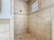 Tiled walk-in shower features a window and decorative trim for a luxurious, spa-like experience at 2209 Callaway Ct, Davenport, FL 33837