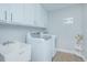 Well-lit laundry room with white cabinets, utility sink, and washer and dryer at 3160 Whisper Wind Dr, St Cloud, FL 34771