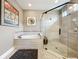 Bright bathroom featuring a soaking tub and glass-enclosed shower with modern fixtures and neutral tiling at 31980 Geoff Way, Sorrento, FL 32776