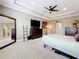 Carpeted bedroom featuring a ceiling fan, bedside tables, dresser, and a large mirror at 31980 Geoff Way, Sorrento, FL 32776
