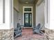 Inviting front porch with brick floor, seating, and stylish front door with decorative glass at 31980 Geoff Way, Sorrento, FL 32776