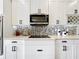 Close-up of kitchen featuring white cabinets, mosaic backsplash, and stainless steel microwave at 31980 Geoff Way, Sorrento, FL 32776