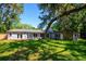 Rear exterior view of the house featuring a large yard with mature trees at 370 Hand Ave, Ormond Beach, FL 32174