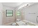 Bright bathroom features a vanity with a large mirror, a combo shower/tub, and neutral tile at 400 Timbercreek N Dr, Winter Garden, FL 34787
