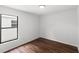 Bright bedroom featuring wood-look floors, a black window frame, and crisp, white walls at 400 Timbercreek N Dr, Winter Garden, FL 34787