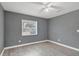 This bedroom is illuminated by a ceiling fan and a window with lovely gray walls and wood floors at 606 Washington St, Daytona Beach, FL 32114