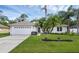Quaint home featuring a two-car garage, solar panels, and mature palm trees at 705 Sunburst Cove Ln, Winter Garden, FL 34787