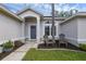 Covered entryway with stylish front door, chairs, and charming landscaping at 705 Sunburst Cove Ln, Winter Garden, FL 34787