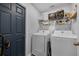 This laundry room includes a white washer, dryer and shelving for storage at 705 Sunburst Cove Ln, Winter Garden, FL 34787