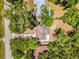 Aerial view of a single-Gathering home surrounded by mature trees, showcasing the property's roof and landscape at 710 N Sparkman Ave, Orange City, FL 32763