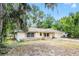 Cozy one-story home featuring a light exterior, attached garage, and mature trees, creating a serene setting at 710 N Sparkman Ave, Orange City, FL 32763
