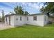 Backyard featuring a white-painted exterior with a green lawn and a chainlink gate at 7612 Pomelo Dr, Orlando, FL 32819
