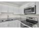 Modern kitchen featuring granite countertops, stainless steel appliances and white cabinetry at 7612 Pomelo Dr, Orlando, FL 32819