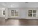 Bright living area featuring laminate wood flooring, three windows, and a freshly painted interior at 7612 Pomelo Dr, Orlando, FL 32819