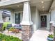Charming front porch with stone-clad columns, stylish seating, and a welcoming entrance with a wreath-adorned front door at 8030 John Hancock Dr, Winter Garden, FL 34787
