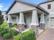 Inviting front porch featuring stone-clad columns, modern furniture, and lush landscaping perfect for enjoying relaxing outdoor living at 8030 John Hancock Dr, Winter Garden, FL 34787