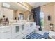 Bathroom featuring dual sinks, large mirrors, white cabinets, and a blue accent rug at 929 Louvre Ct, Kissimmee, FL 34759
