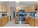 Well-lit kitchen featuring stainless steel appliances, tile floors and countertops, and wooden cabinets at 929 Louvre Ct, Kissimmee, FL 34759
