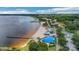 Aerial view showcasing a sandy beach and lakeside park with splash pad and playground amenities by a serene lake at 10697 Lake Hill Dr, Clermont, FL 34711