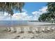 Inviting beach with white sand and chairs overlooking a serene lake and pier at 10697 Lake Hill Dr, Clermont, FL 34711