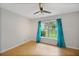 Cozy bedroom with a ceiling fan, wood flooring, and a bright window adorned with curtains at 10697 Lake Hill Dr, Clermont, FL 34711