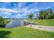 Concrete boat ramp with wooden docks alongside a scenic lake under a partly cloudy sky, framed by green grass at 10697 Lake Hill Dr, Clermont, FL 34711