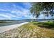 Sandy lakeshore with a concrete pier leading to a wooden dock under a blue, partly cloudy sky at 10697 Lake Hill Dr, Clermont, FL 34711