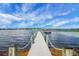 Picturesque view of a wooden dock with chain railing extending into the calm lake waters at 10697 Lake Hill Dr, Clermont, FL 34711