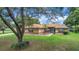 Charming single-story home with a well-manicured lawn, blue front door, and mature trees providing ample shade at 10697 Lake Hill Dr, Clermont, FL 34711