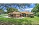 Charming single-story home featuring a manicured lawn, mature trees, and a welcoming blue front door at 10697 Lake Hill Dr, Clermont, FL 34711