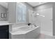 Elegant bathroom featuring a soaking tub, glass-enclosed shower, plantation shutters, and neutral tile, creating a spa-like atmosphere at 1224 Hillcrest View Loop, Apopka, FL 32703