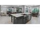 Open-concept kitchen featuring a gray island with a stainless steel sink, extending to living and dining spaces with bright natural light at 1224 Hillcrest View Loop, Apopka, FL 32703