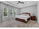 Serene main bedroom with a large bed, tray ceiling, soft carpet, and three windows offering ample natural light at 1224 Hillcrest View Loop, Apopka, FL 32703