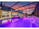 Stunning screened pool and spa with waterfall features are beautifully lit by vivid purple lights at twilight at 1224 Hillcrest View Loop, Apopka, FL 32703