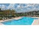 Community pool with lounge chairs, umbrellas, and lush landscaping on a sunny day at 15133 Summer Harvest St, Winter Garden, FL 34787