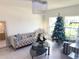 Bright living room with a tufted sofa, modern coffee table, and a festive Christmas tree near the windows at 1588 Sky Lakes Dr, St Cloud, FL 34769