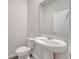 Modern bathroom with white pedestal sink, toilet, and large frameless mirror at 172 S Zuni Rd, St Cloud, FL 34771