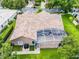 Aerial view of a home featuring a tile roof and screened patio, nestled amongst lush greenery at 174 Promenade Cir, Lake Mary, FL 32746