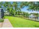 Manicured backyard with lush green grass, mature trees, and a serene pond view at 174 Promenade Cir, Lake Mary, FL 32746