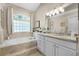 Bathroom with a soaking tub, decorative window, and marble vanity with updated fixtures and ample storage at 174 Promenade Cir, Lake Mary, FL 32746