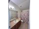 Well-lit bathroom featuring a functional single sink vanity, toilet, and shower with a floral curtain at 1984 Estancia Circle # 29A, Kissimmee, FL 34741