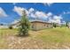 View of the rear of the home surrounded by a well-maintained lawn under a partly cloudy sky at 205 Cimarron Dr, Kissimmee, FL 34759