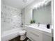 Well-lit bathroom featuring a white vanity, and a tub with elegant marble-style tile surround at 2160 Churchill Downs Cir, Orlando, FL 32825