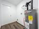 Utility room with a modern water heater and wood-look flooring, plus a door to the outside at 2160 Churchill Downs Cir, Orlando, FL 32825