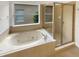Bright bathroom featuring a soaking tub beneath a window and a glass-enclosed shower at 2679 Rainbow Springs Ln, Orlando, FL 32828