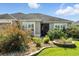 Inviting home featuring decorative shrubbery, a well-manicured lawn, and a dark front door at 2895 Apache Ct, The Villages, FL 32163