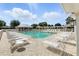 Community pool with lounge chairs and umbrellas with a clubhouse in the background at 2895 Apache Ct, The Villages, FL 32163