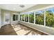 Sunroom featuring multiple windows offering views of lush landscaping and wood-look floors at 2895 Apache Ct, The Villages, FL 32163